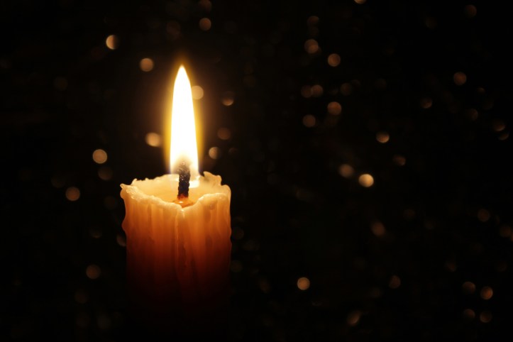 White Candles Burning in the Dark with focus on single candle in foreground.